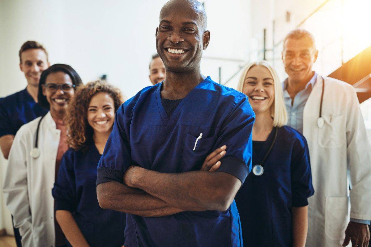 Smiling African doctor standing in a hospital with his staff