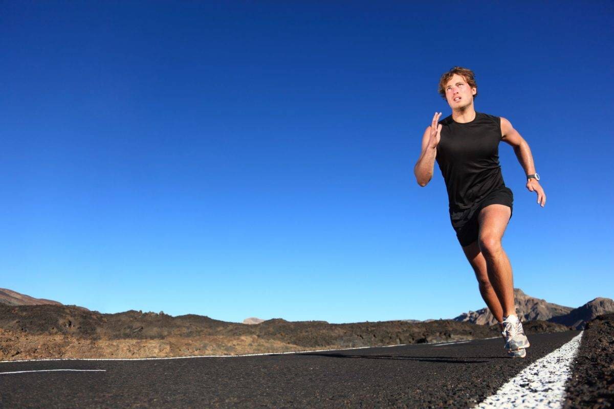 Running man. Male runner at sprinting speed training for marathon outdoors in amazing volcanic dessert landscape. 