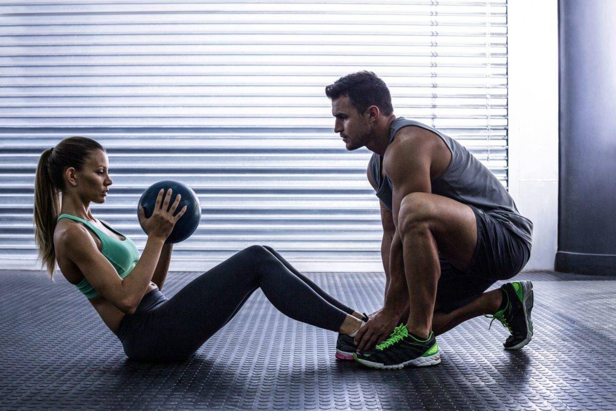 Side view of a muscular couple doing abdominal ball exercise