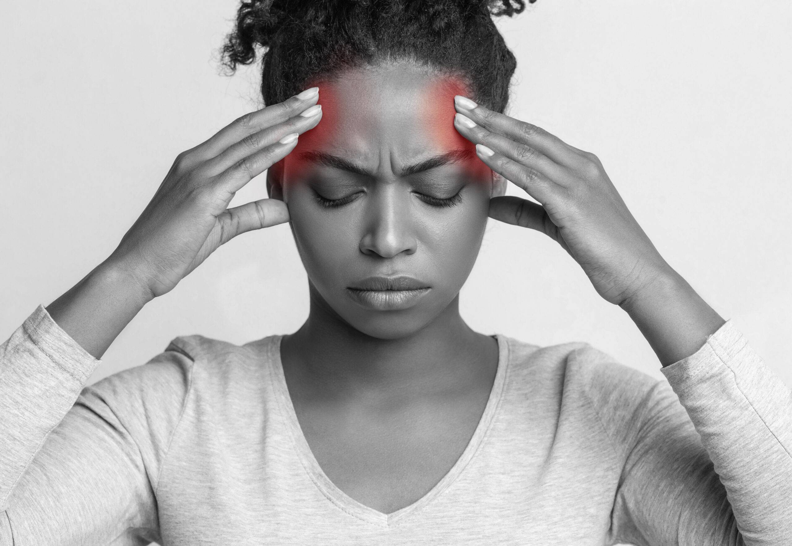 Afro girl with headache touching her highlighted temples, emotional black and white photo